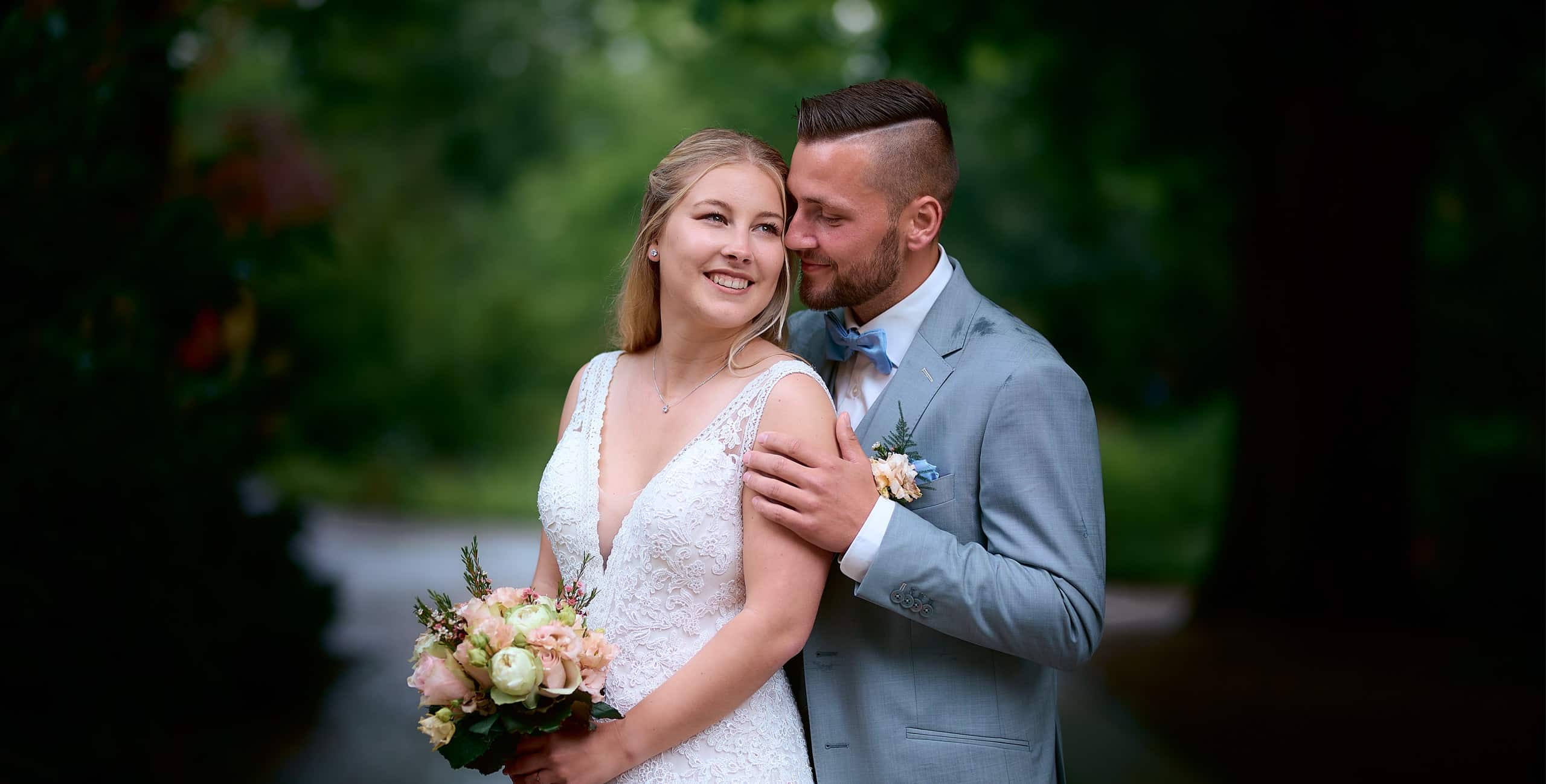 Hochzeitsfotograf Villingen-Schwenningen ein Brautpaar, dass sich leidenschaftlich in den Armen liegt.. Der Bräutigam trägt einen hellblauen Anzug und die Braut ein weißes Kleid.